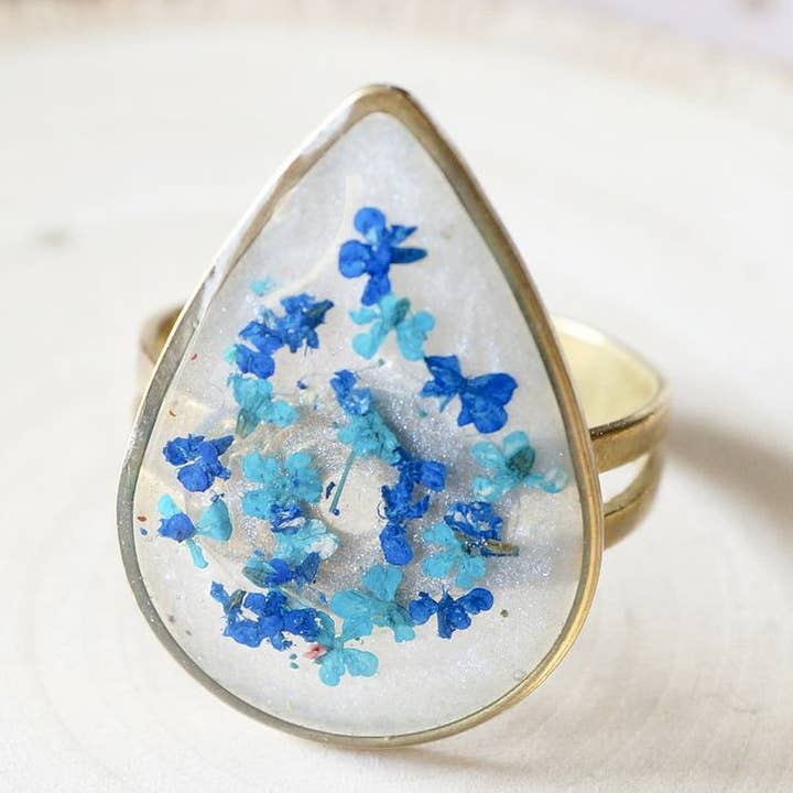 Gouden teardrop in groenblauw en blauwe echte geperste bloemen in harsring voor wholesale door Ann + Joy